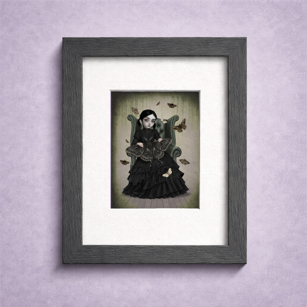 A Framed  2.5x3.5 inch ACEO art trading card featuring a gothic girl in a black Victorian dress sitting in an armchair with giant moths.