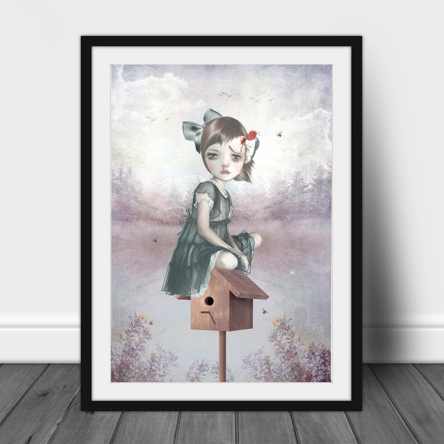 Large black-framed surreal art print of a girl sitting on a birdhouse with a woodpecker pecking her head, leaning against a wall for a bold, artistic display.