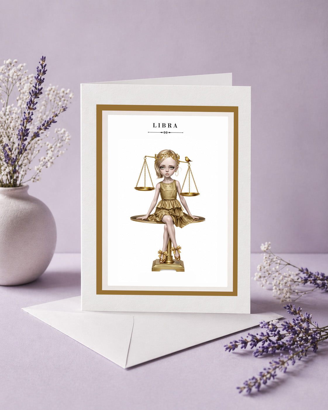 Libra zodiac birthday card featuring an illustration of a blonde maiden in a metallic gold dress sitting atop a golden balance scale with a tiny bird.
