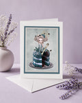 Greeting card with a decorative design of Marie Antoinette part cake, surrounded by lavender flowers on a light purple background.