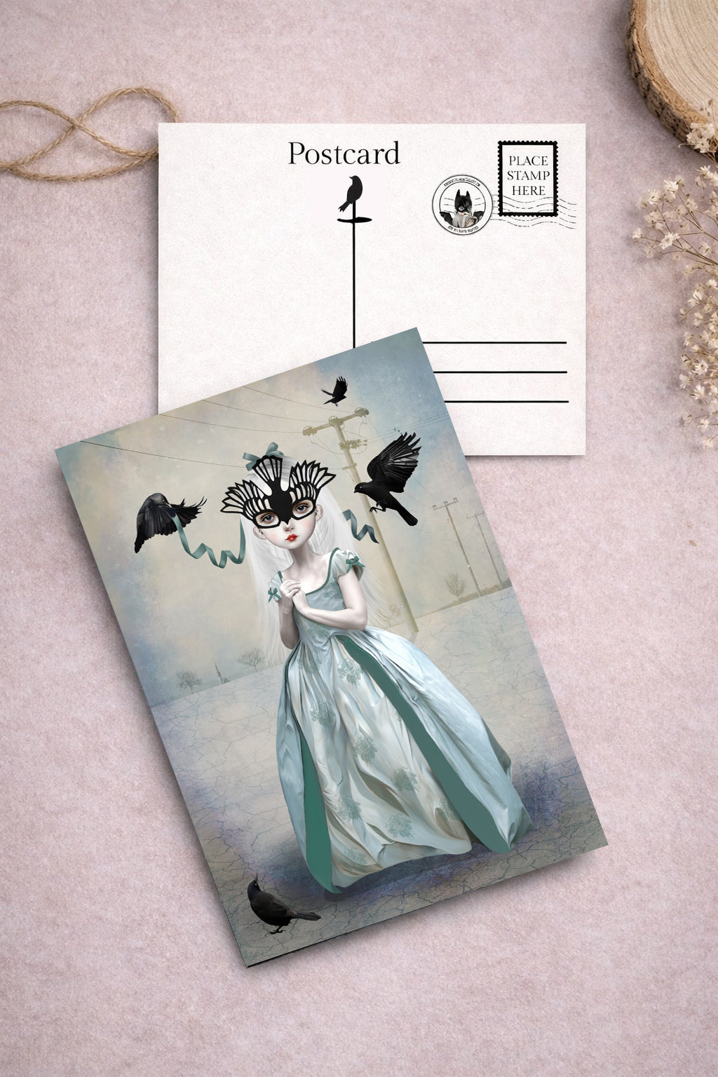 Postcard with illustration of a woman in a blue dress and mask, surrounded by birds.