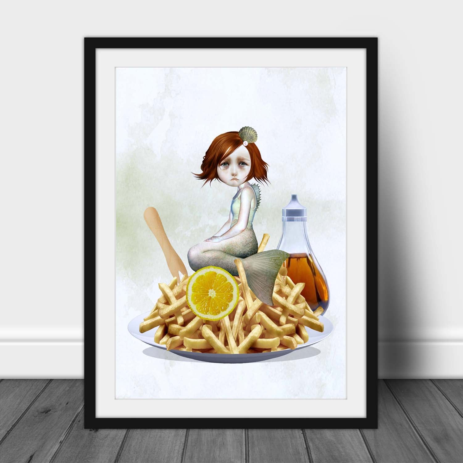 Framed artwork of a mermaid sitting on chips with a bottle of vinegar and lemon slice.