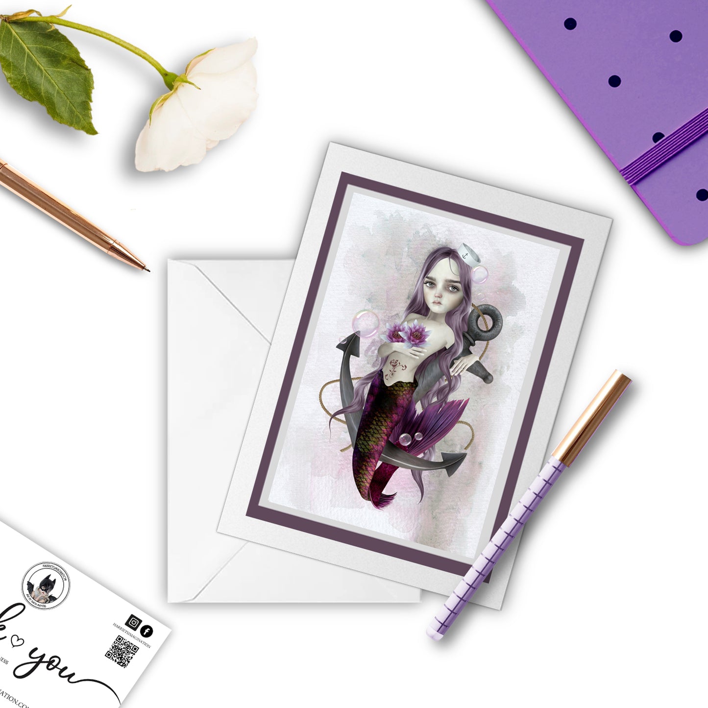 Mermaid and anchor greeting card beside a notebook and pen – perfect for gifting or writing a nautical, poetic note.