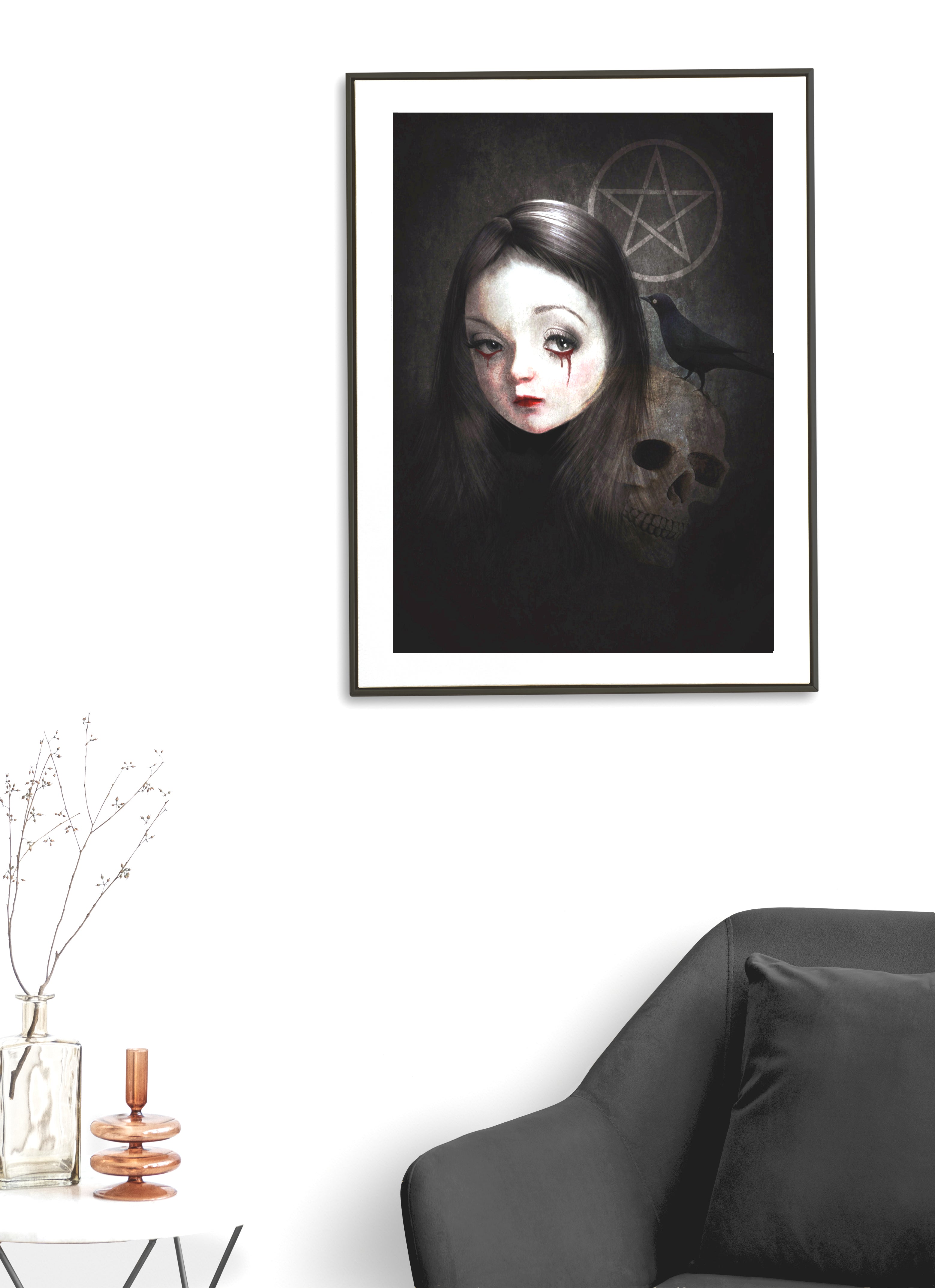 Framed  gothic art print on a living room wall on display featuring a stylized girl with bloody tears, a skull, blackbird, and pentacle