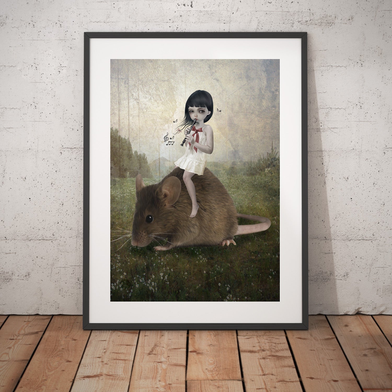Girl and mouse art print in a black frame, standing against a white wall.