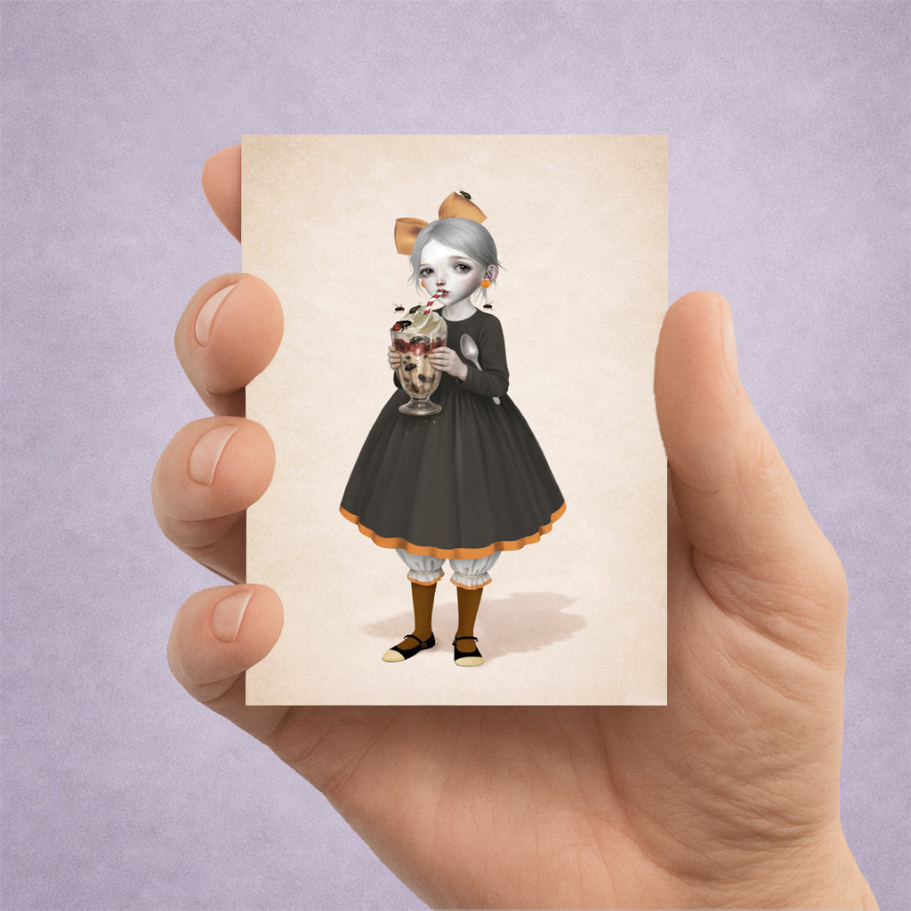 Hand holding a creepy cute pop surreal ACEO art card featuring a girl with a beetle sundae.