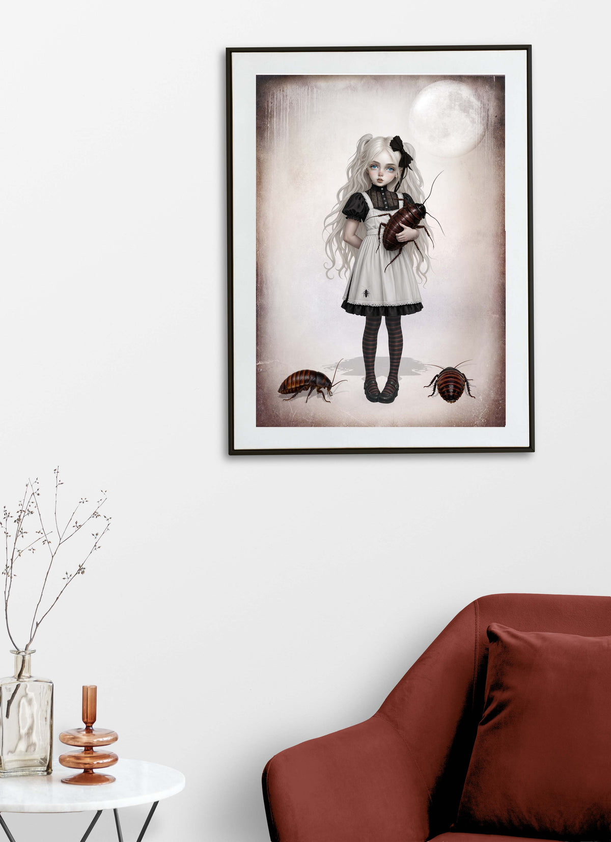 Fine art print of a whimsical gothic girl with pigtails holding a giant cockroach against a pale moon backdrop on display on a living room wall.