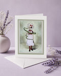 Greeting card with a eyepatch girl with a snake coiled around her, surrounded by lavender and white flowers on a light purple background.