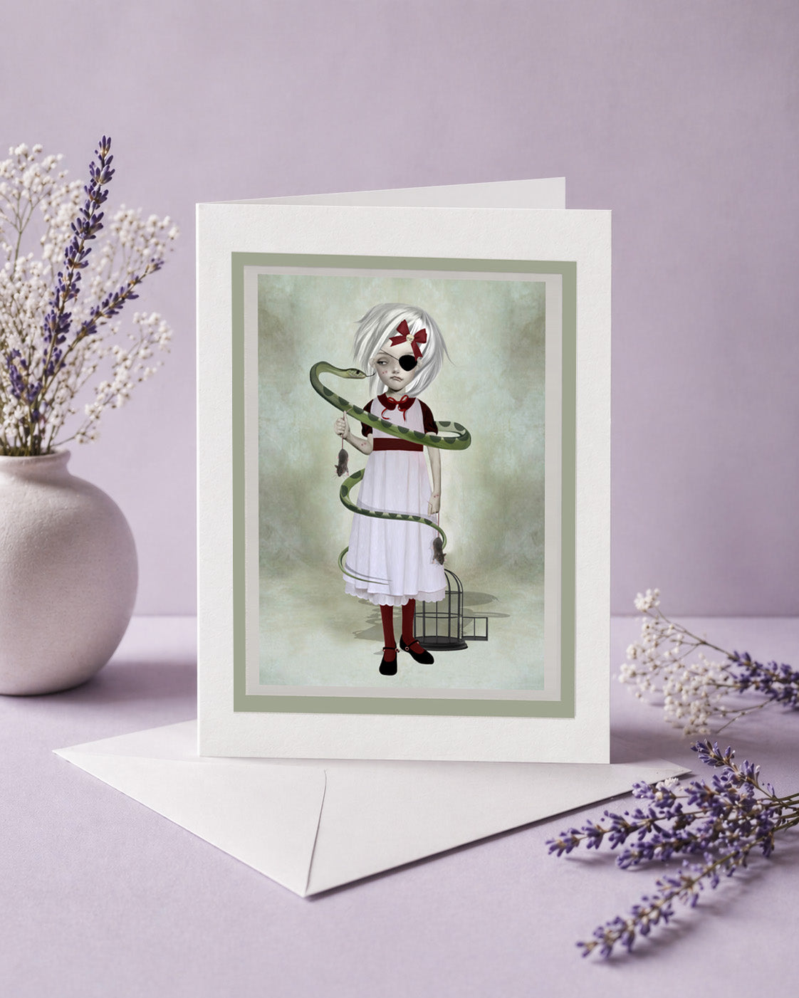 Greeting card with a eyepatch girl with a snake coiled around her, surrounded by lavender and white flowers on a light purple background.