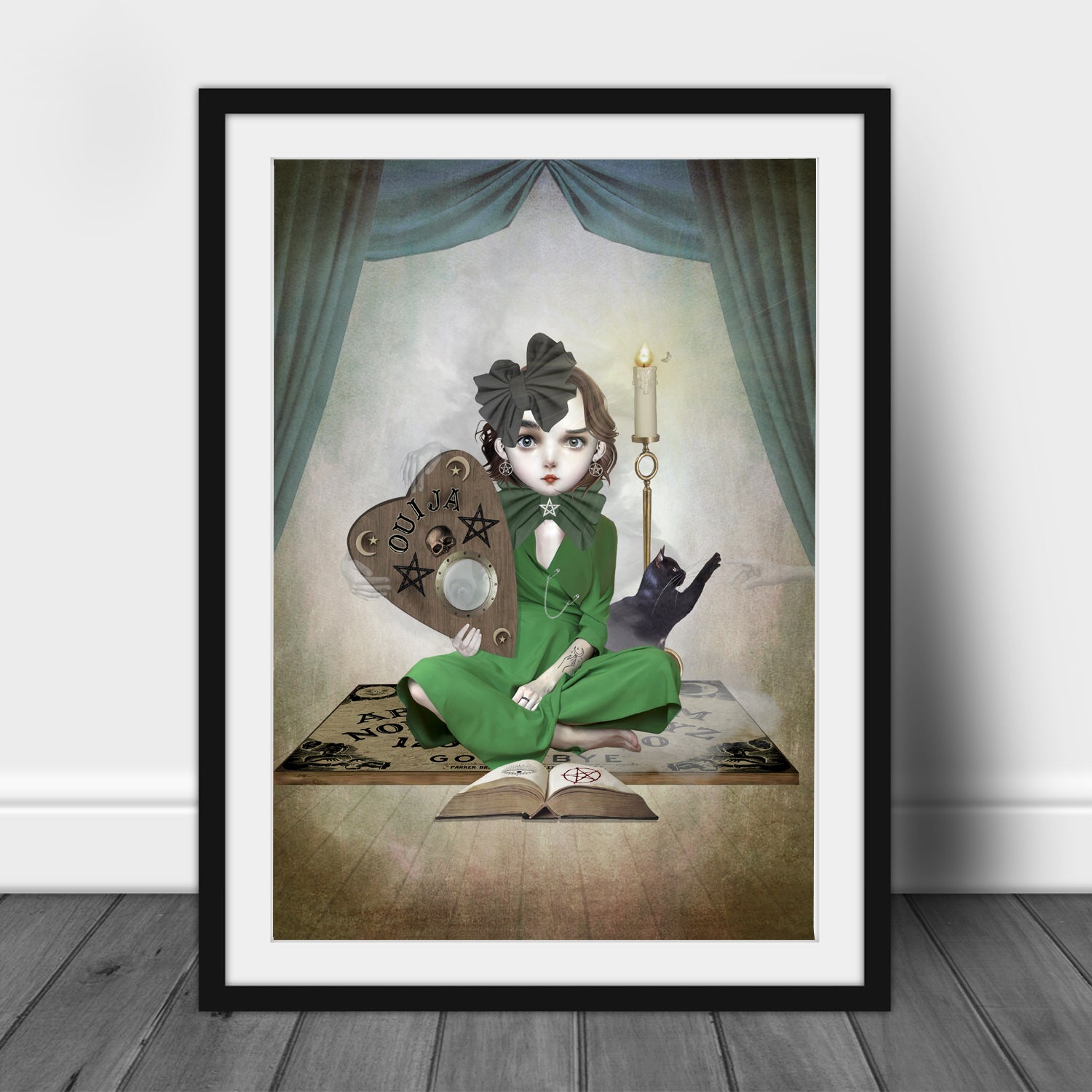 Art print of a girl and ouija board, in a frame, leaned against a wall.