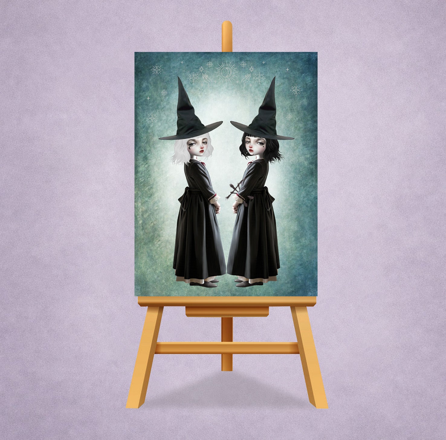 Miniature 2.5x3.5 ACEO art card on small display easel stand, featuring twin gothic witches with white and black hair against a celestial teal background.