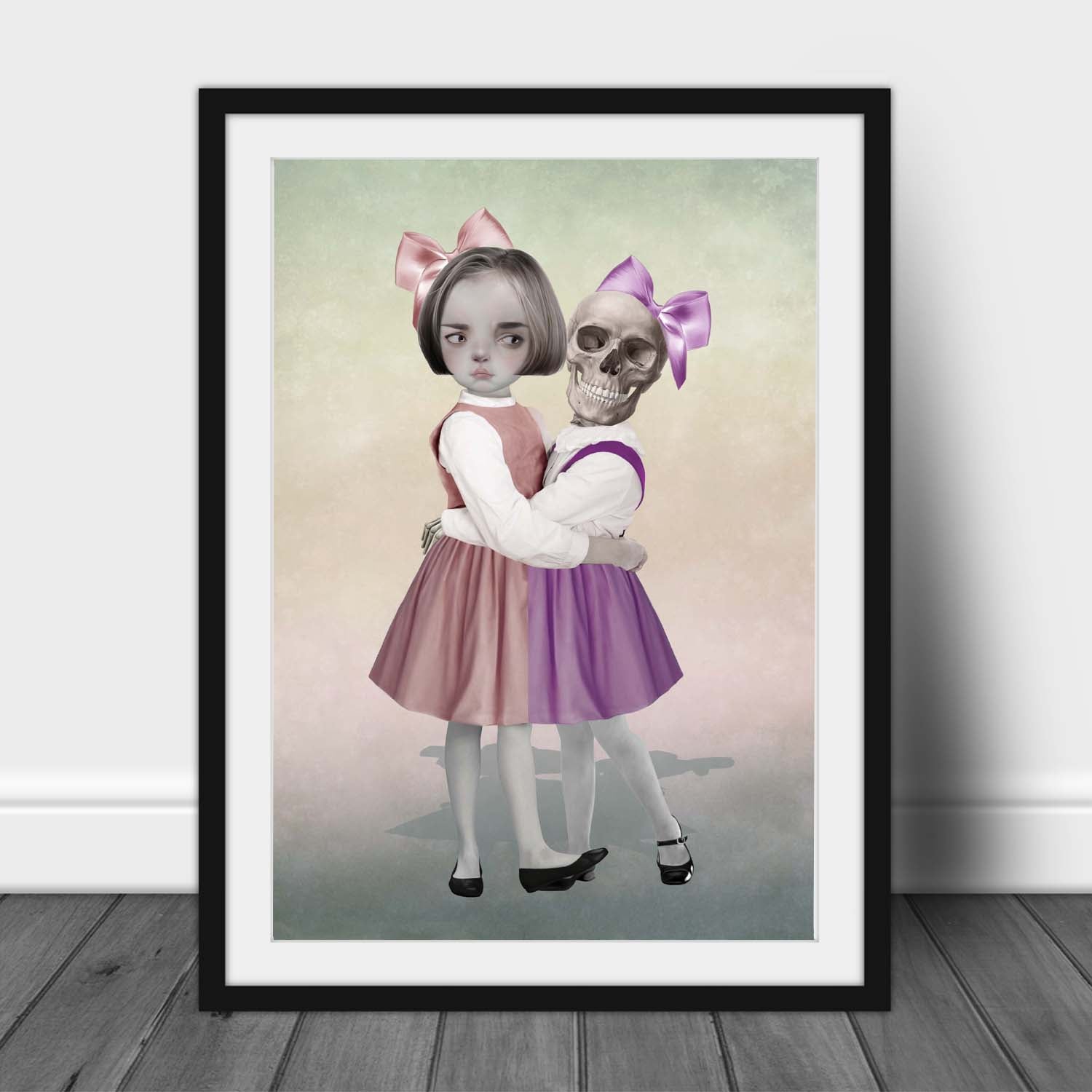 Art print of a skeleton girl and friend, in a frame, leaned against a wall.