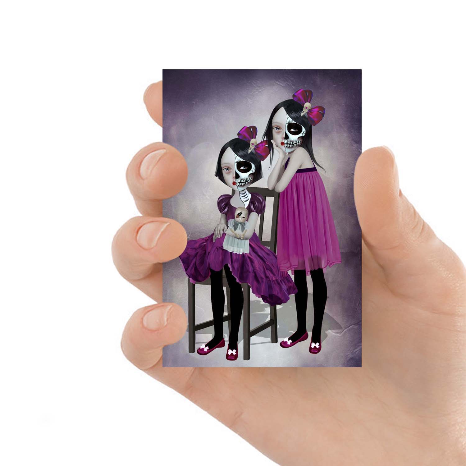 ACEO art card featuring two sisters wearing skull face art, held in hand—creepy cute gothic art style with dark, whimsical elements.
