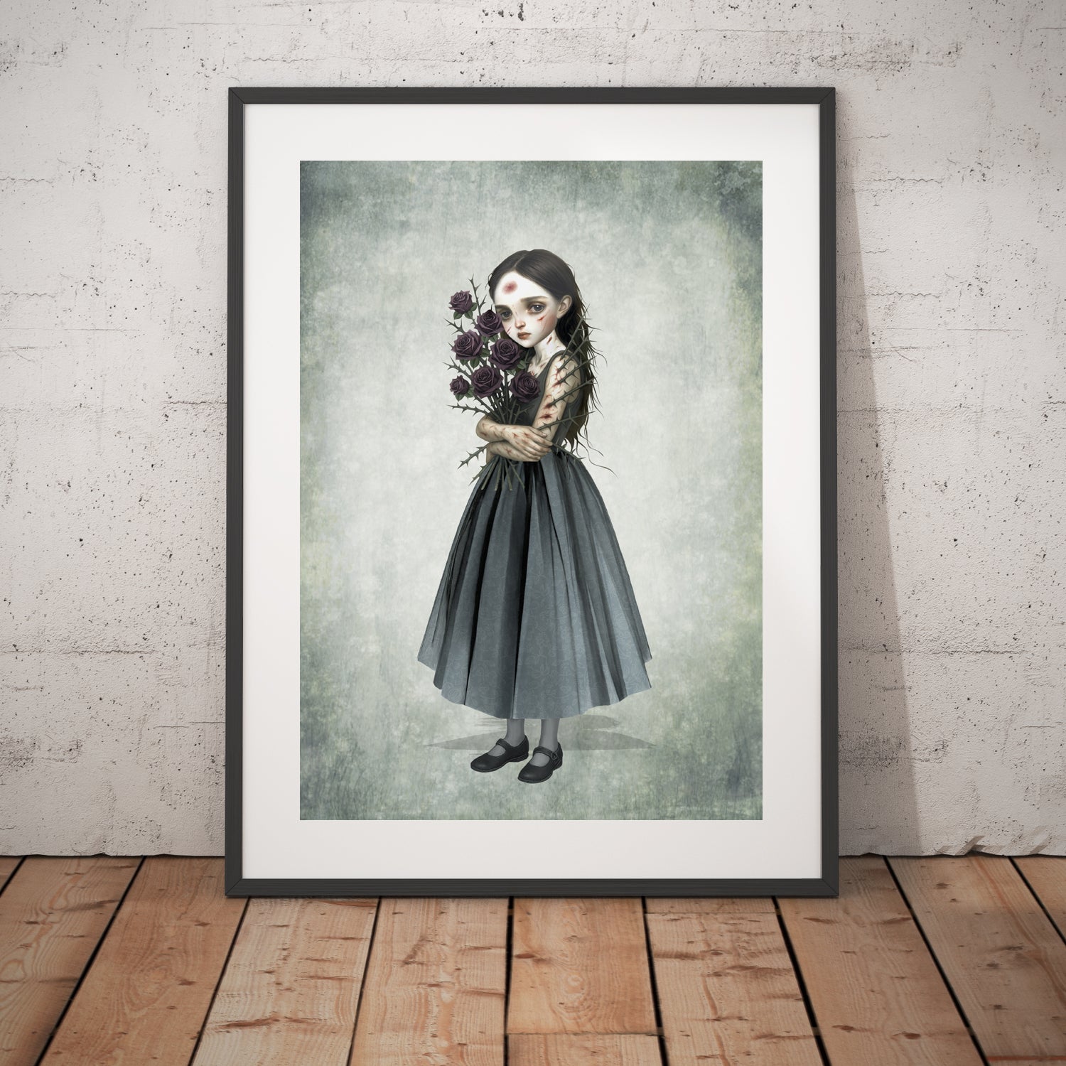 Surreal art print of a girl with a thorny rose bouquet, framed in black and displayed against a white brick wall.