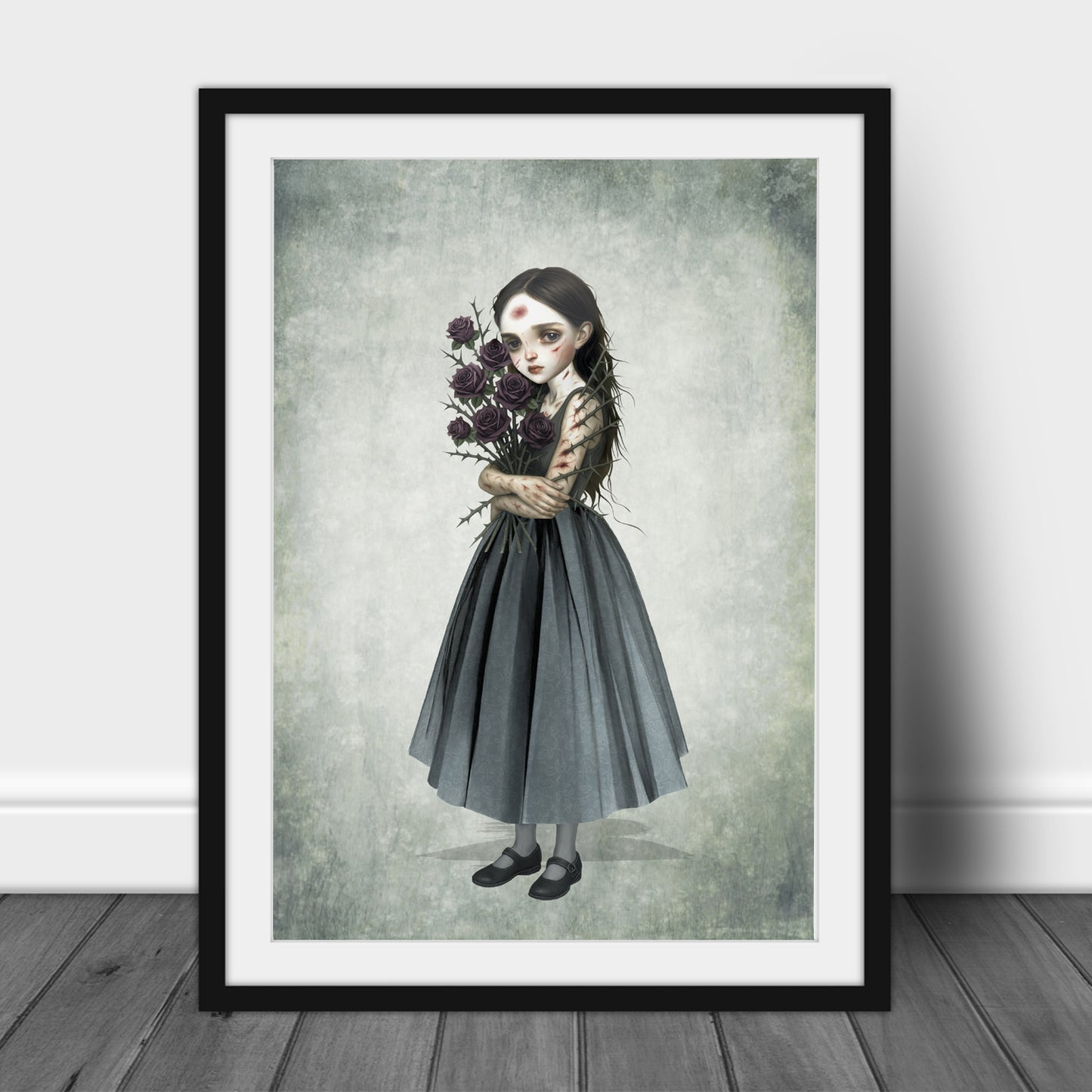 Surreal art print of a girl with a thorny rose bouquet, framed in black and displayed against a white wall.