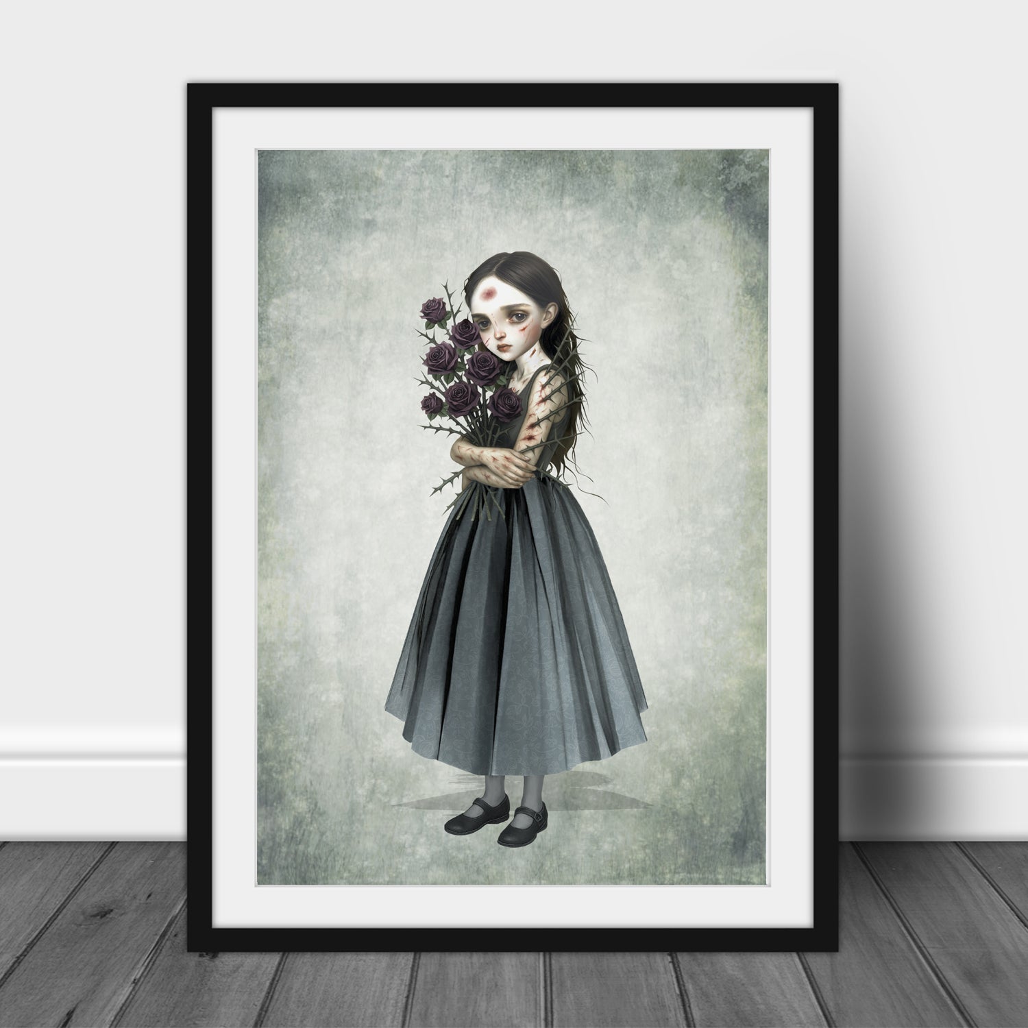 Surreal art print of a girl with a thorny rose bouquet, framed in black and displayed against a white wall.