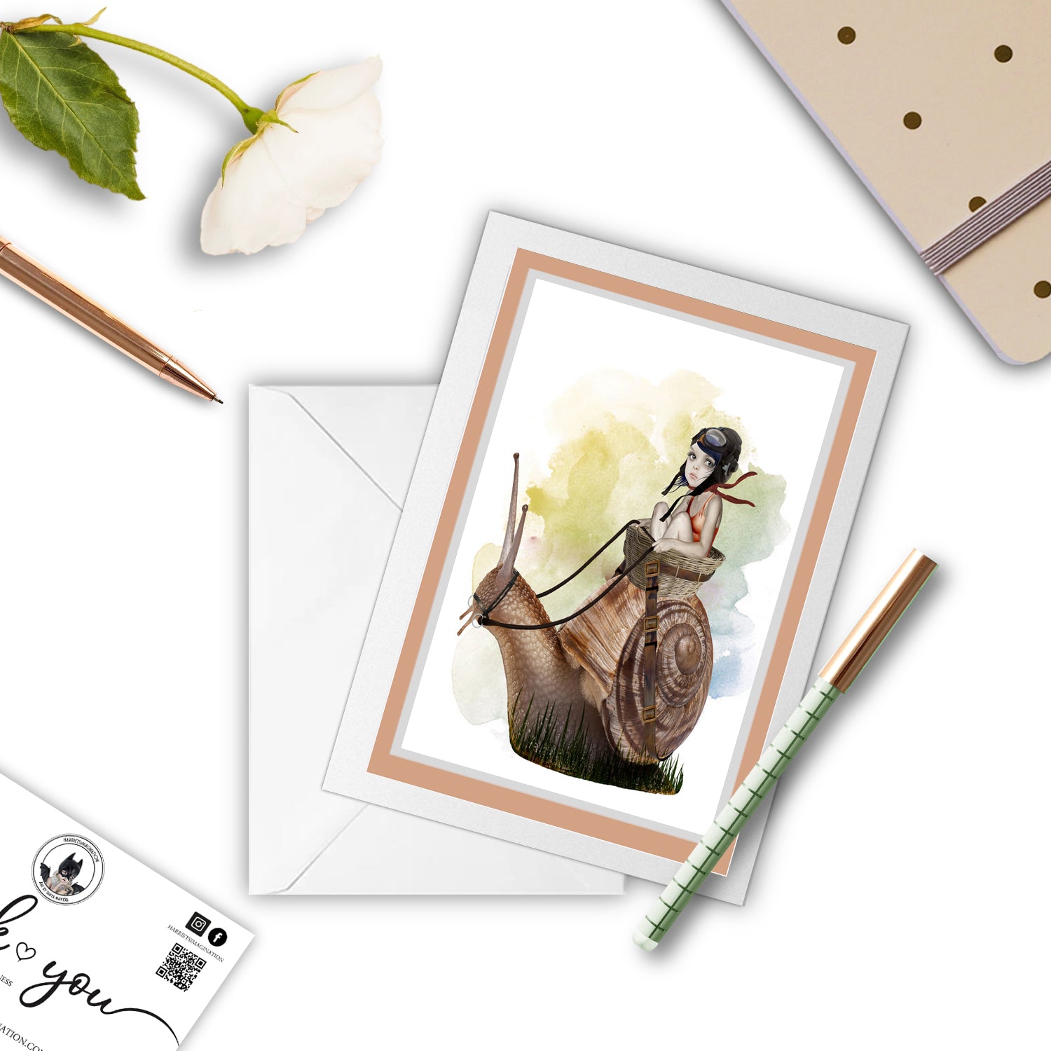 Surreal Garden Snail Greeting Card with pen, and other stationary items around it.