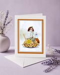 Greeting card with a quirky illustration of a mermaid among fries and a vinegar bottle, placed on a surface with decorative elements.