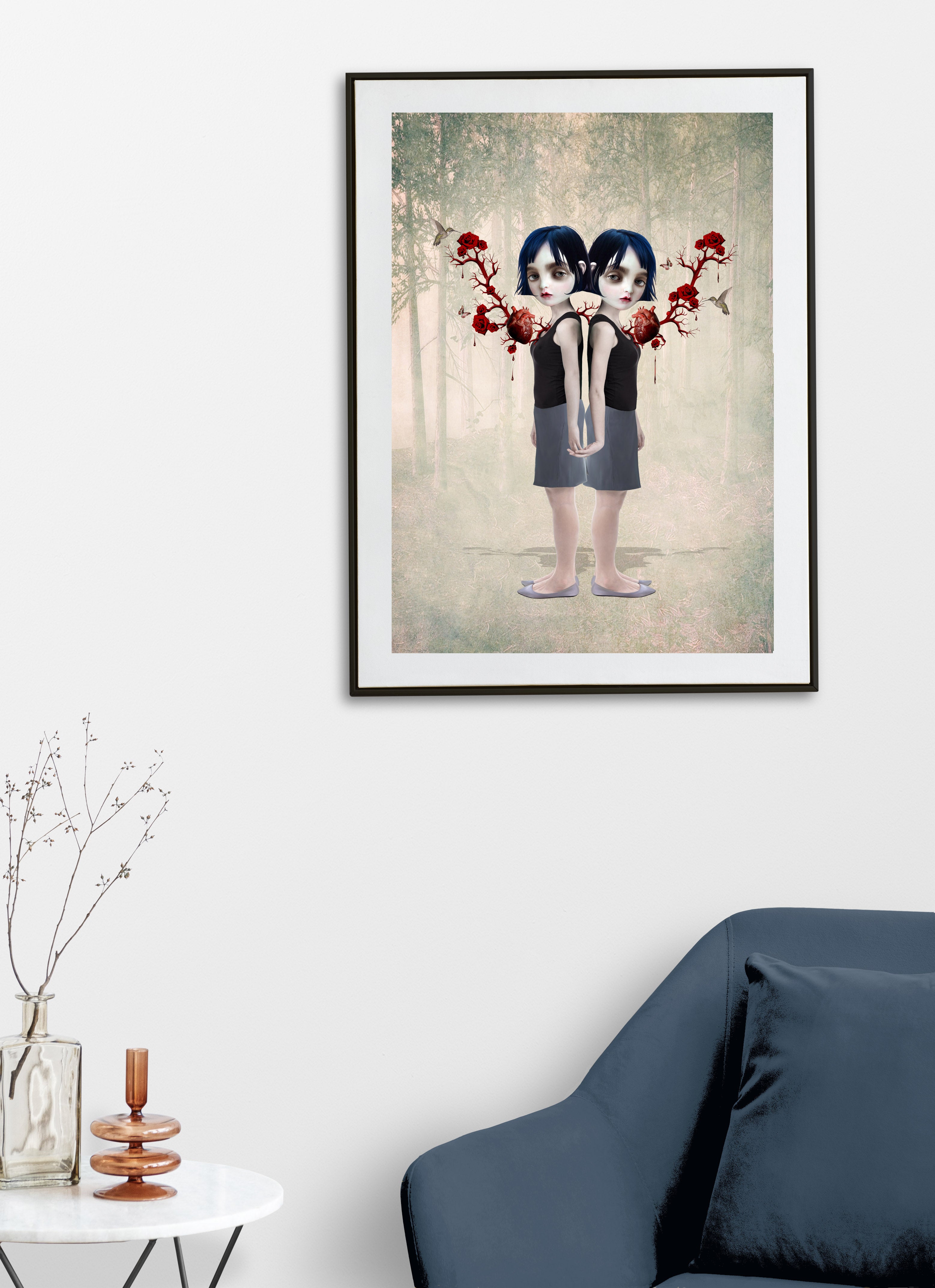 Framed artwork of twin sisters anatomical hearts and  flowers on a wall above a blue sofa.