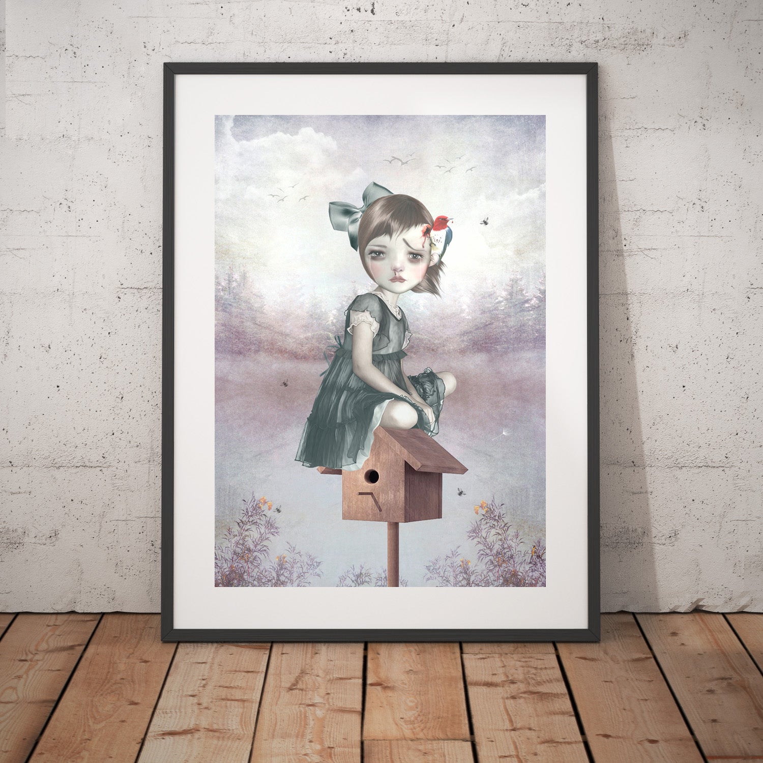 Surreal art print framed and placed against a wall, depicting a girl sitting on a birdhouse with a woodpecker pecking her head, blending whimsy and fantasy.