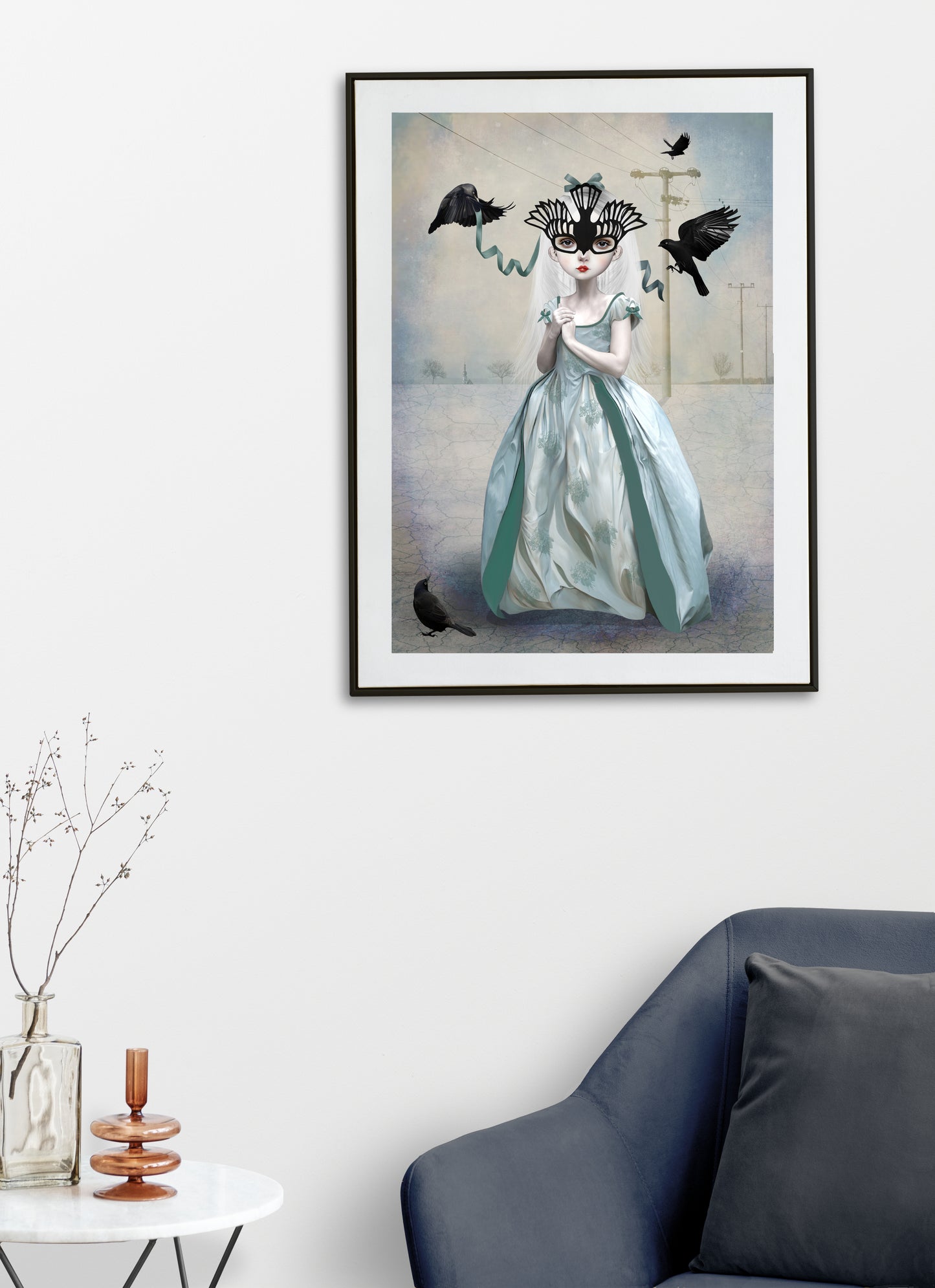  Framed blackbird art print on living room wall featuring a girl in a blue gown adorned with a blackbird mask surrounded by blackbirds. 