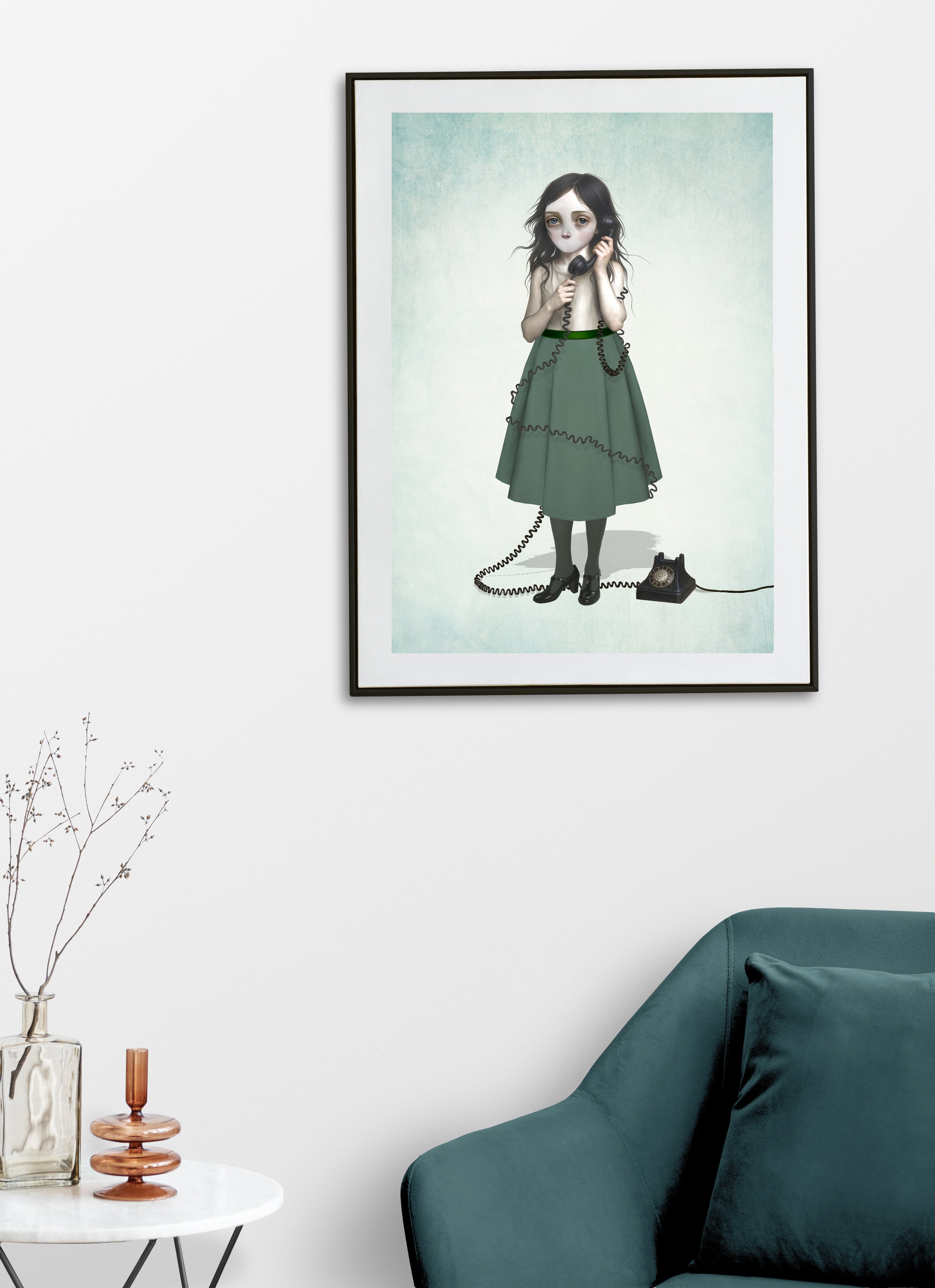 Framed artwork of a girl in a green dress with a telephone and no mouth on a white wall above a teal sofa.