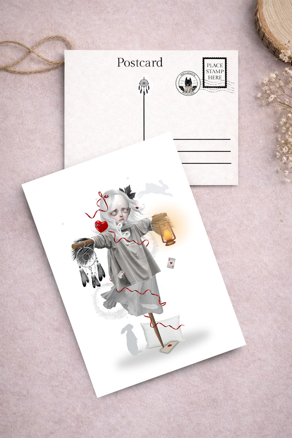 Art postcard on a pink surface, one with an illustration of a girl scarecrow holding a lantern, she is the dream keeper ready to scare bad dreams away.
