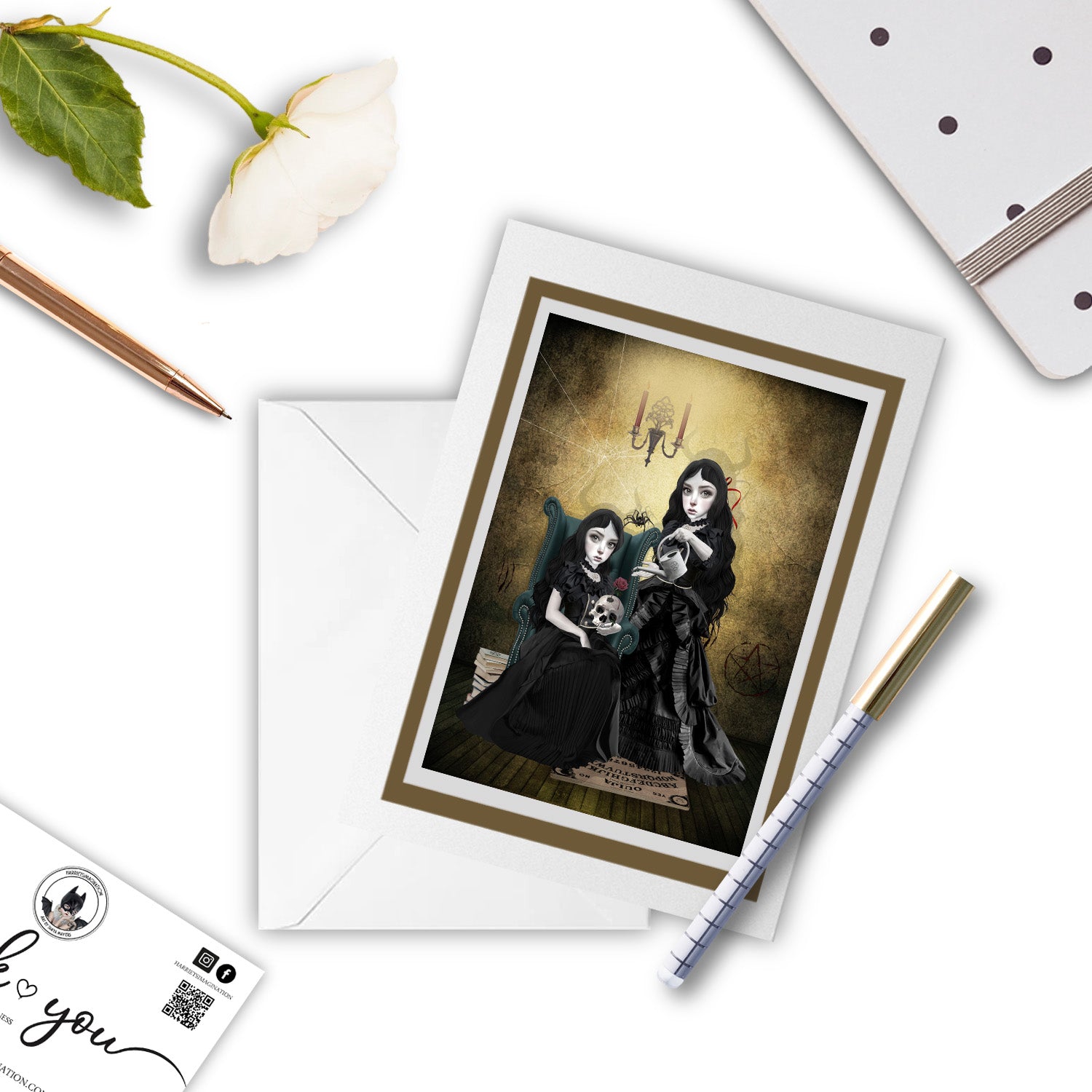 two sister witches preparing for the witching hour, greeting card beside a notebook and pen – perfect for gifting or writing a dark, poetic note.