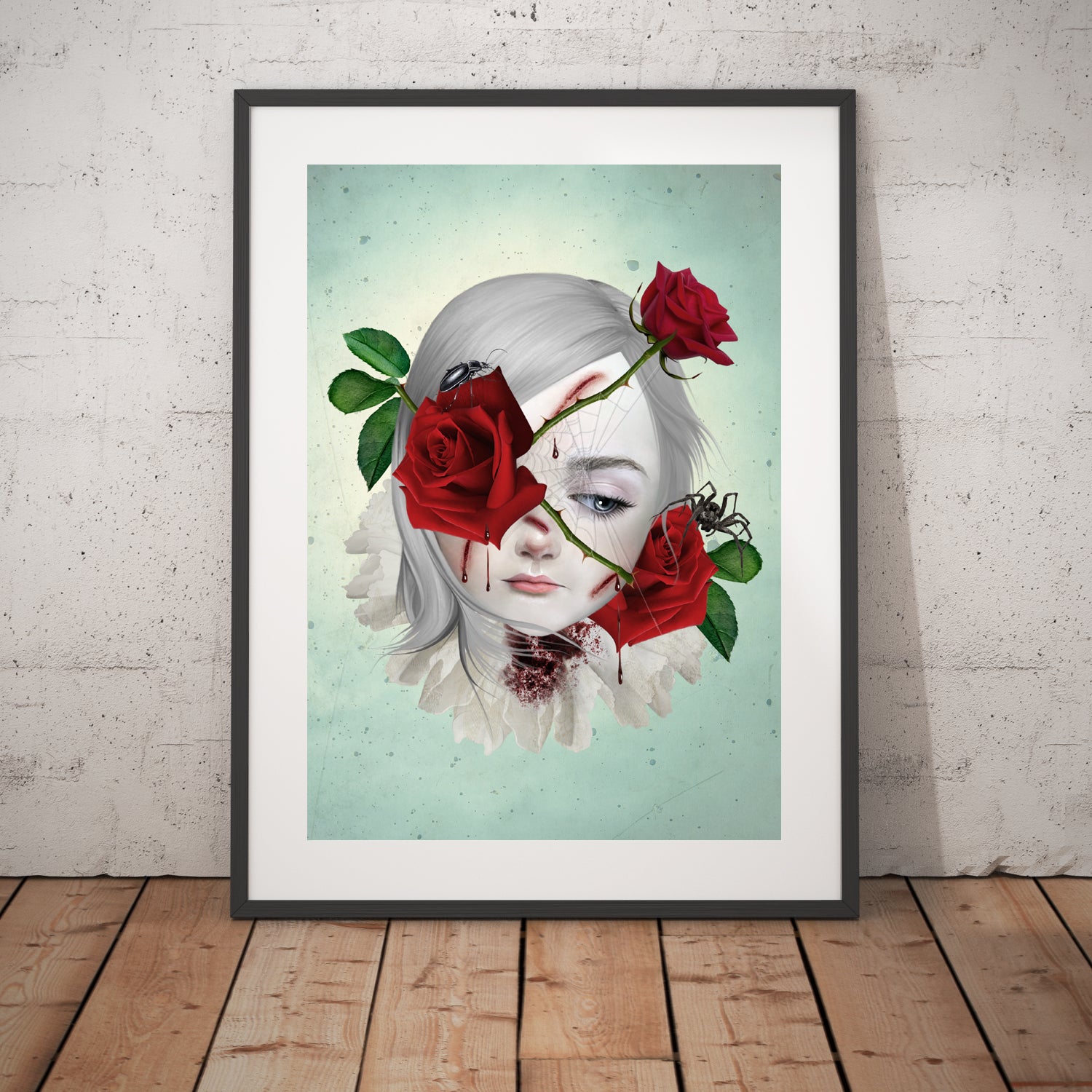 Surreal art print of a girl with thorny red roses bleeding from the thorns, surrounded by a spider and beetle, displayed in a large black frame, leaning against a white wall. This emotional dark fantasy piece evokes depth and symbolism.