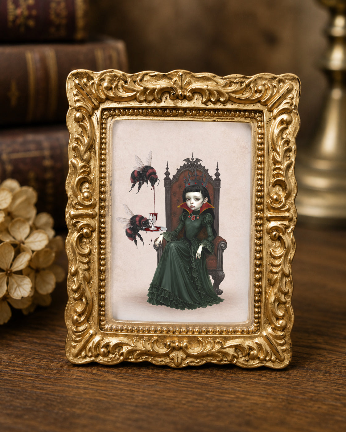 Miniature 1:12 scale gothic art print in an ornate gold frame featuring a dark queen on a throne with red bumblebees pouring blood into a cup, displayed in a dollhouse setting.