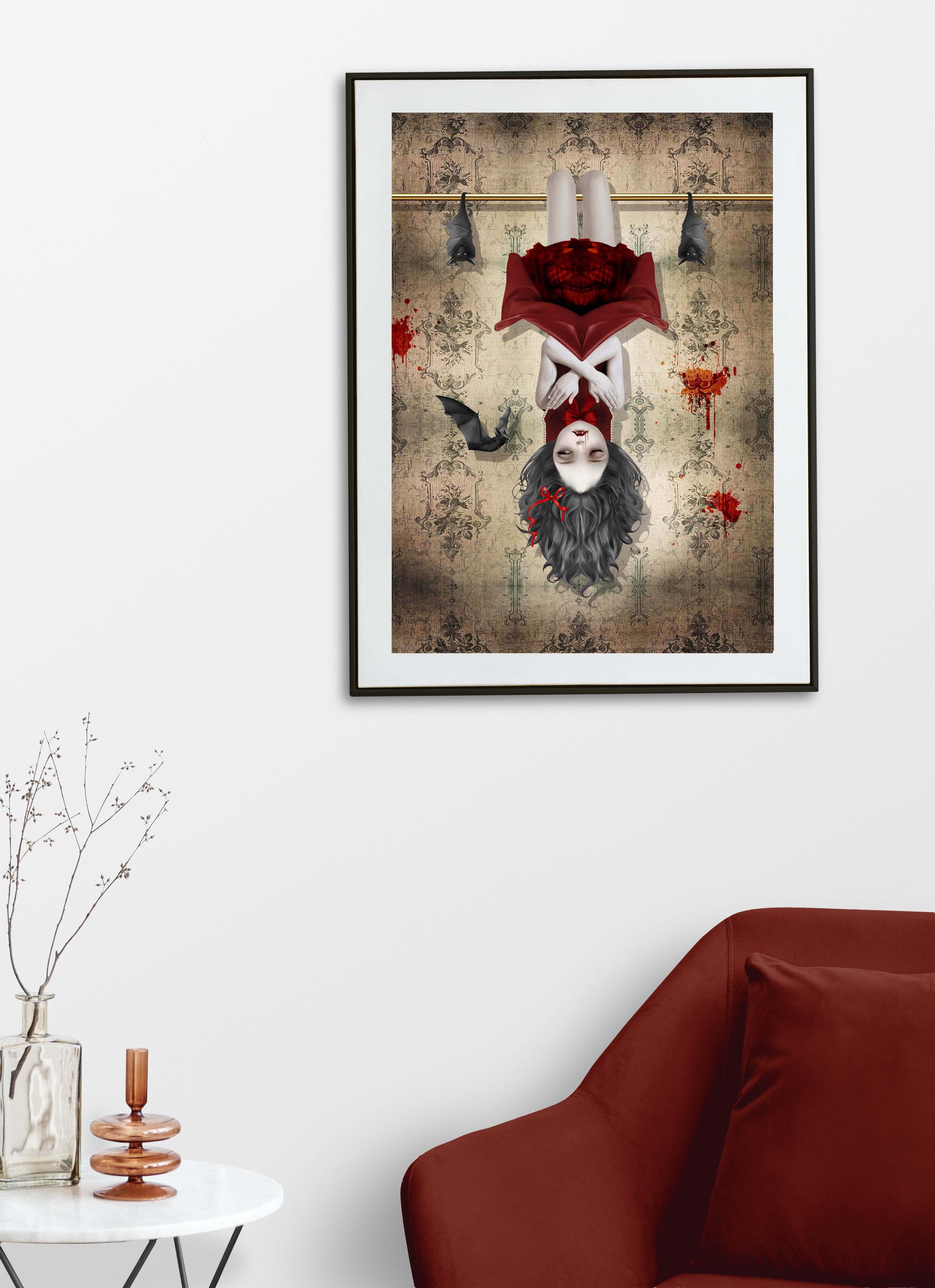 Framed gothic vampire girl and bats wall art displayed above a red chair in a minimalist room with dark whimsigoth decor styling.