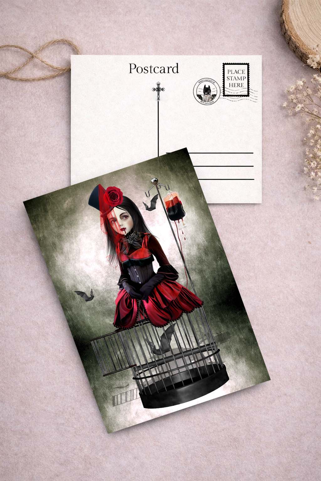 Postcard with a stylized illustration of a vampire in a red outfit and black hat, with a birdcage on a textured surface.