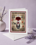 Greeting card with a surreal design of a vampire girl and bats hanging upside down, surrounded by flowers on a light purple background.