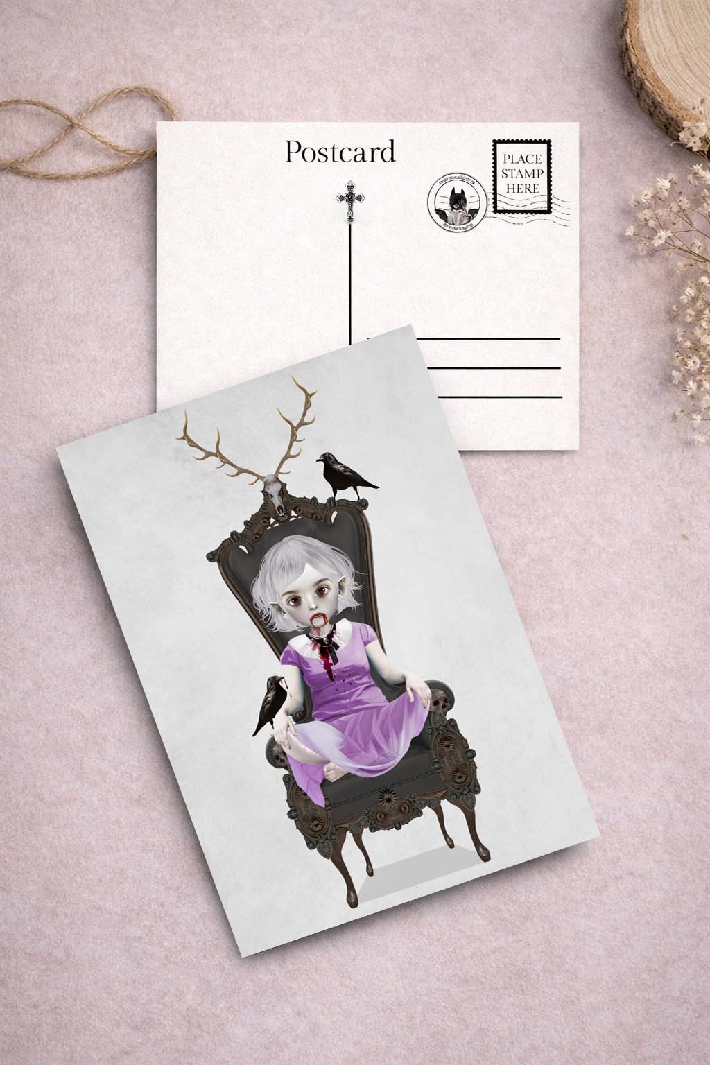Postcard with a bloody vampire girl on an ornate chair and Ravens, placed on a textured surface.