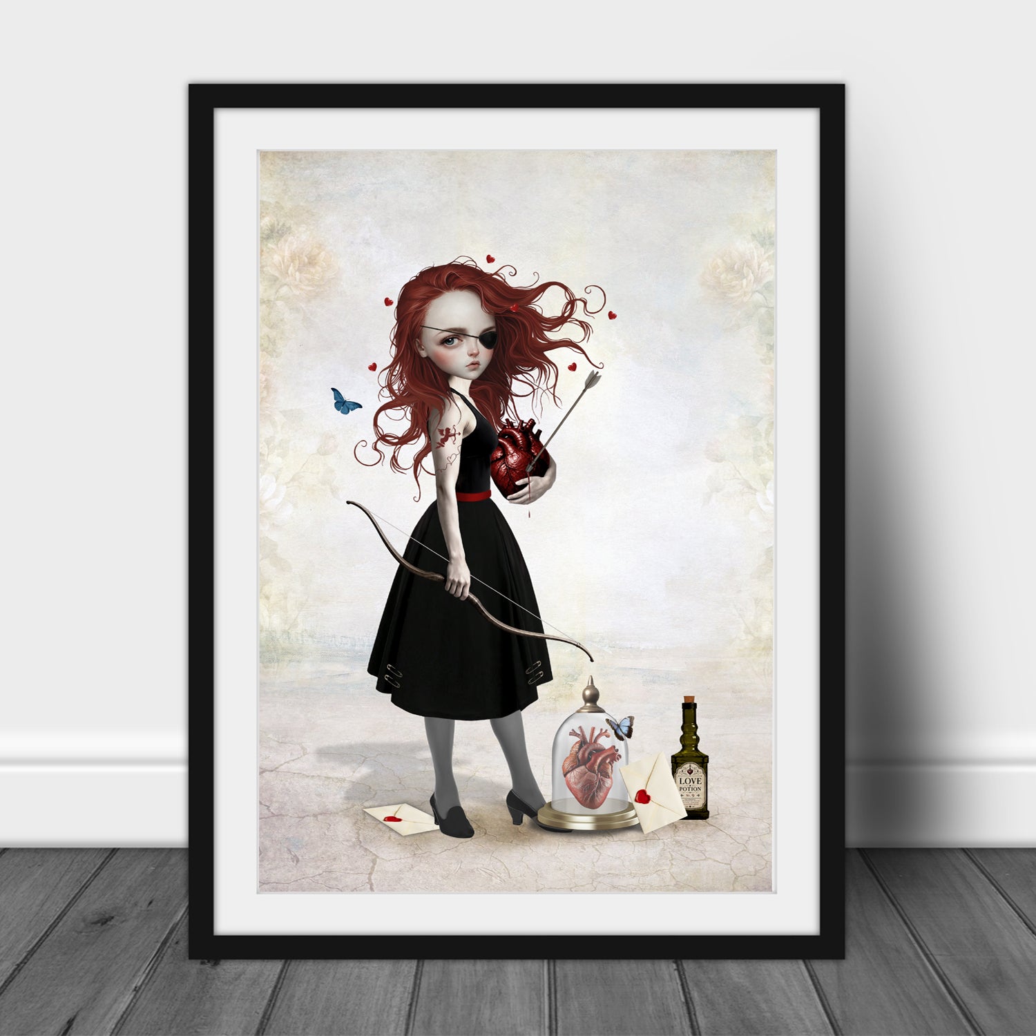 Pop Surrealism art print in an A3 frame featuring a redhead girl with an eye patch holding a bow and arrow and a bleeding anatomical heart, alongside a love potion bottle.