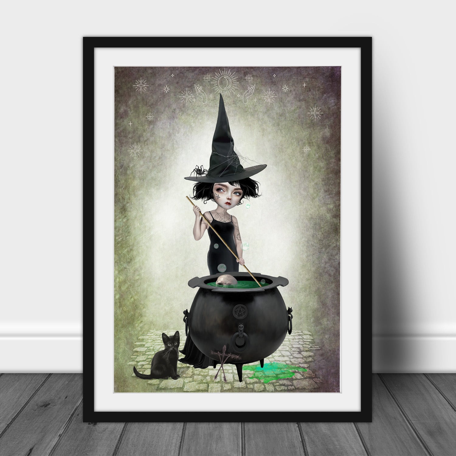 Framed gothic art print. A witch stirs her potions in her bubbling cauldron, while her black cat keeps a close eye on things.