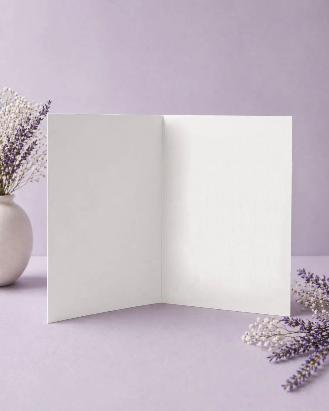 Open white card on blank ready for your personal message on a light purple background with lavender flowers.