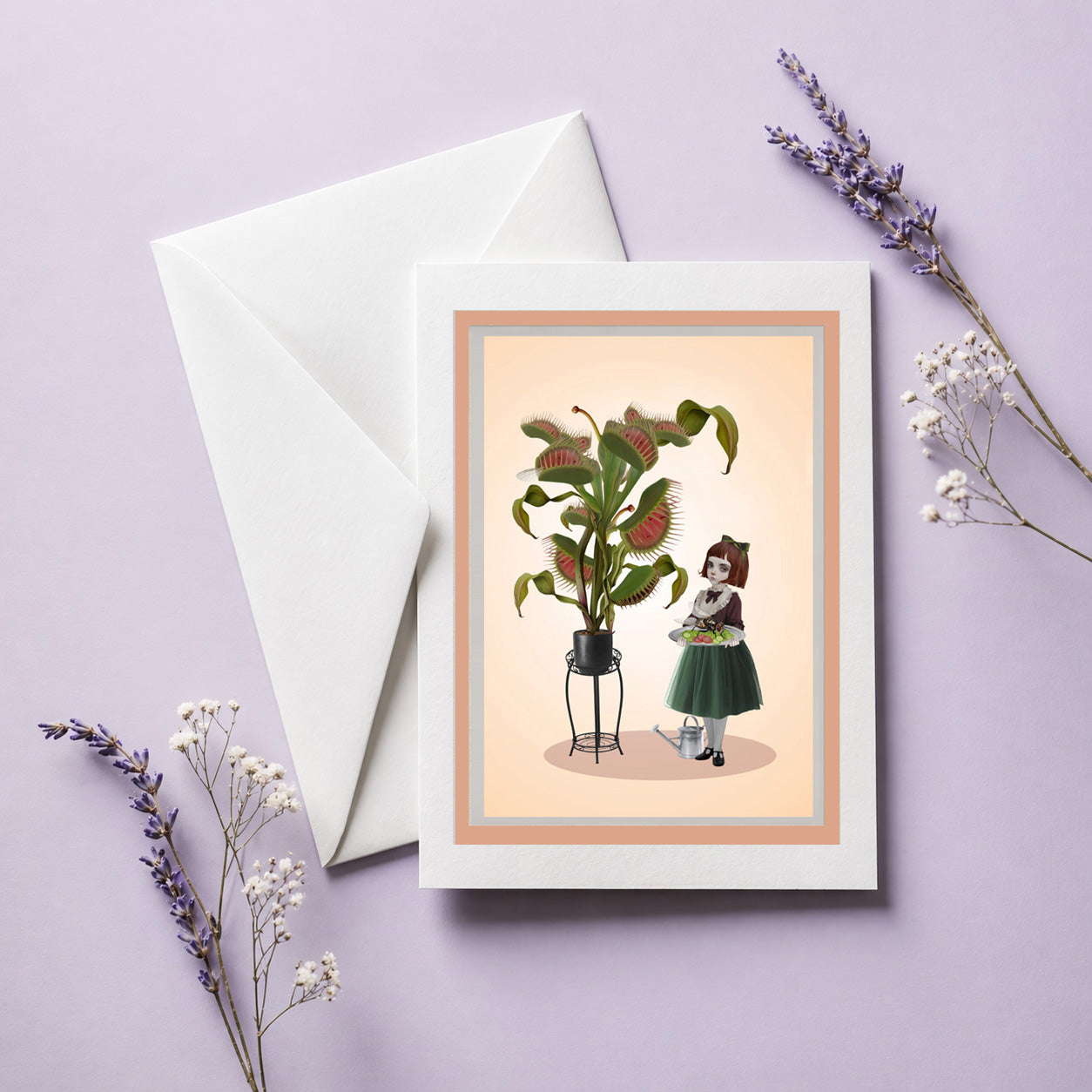 Greeting card with a quirky illustration of a girl interacting with a carnivorous plant, placed on a light purple surface with white envelope and dried flowers.