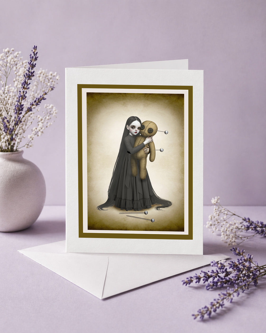 voodoo doll art greeting card on envelope against a lilac background.